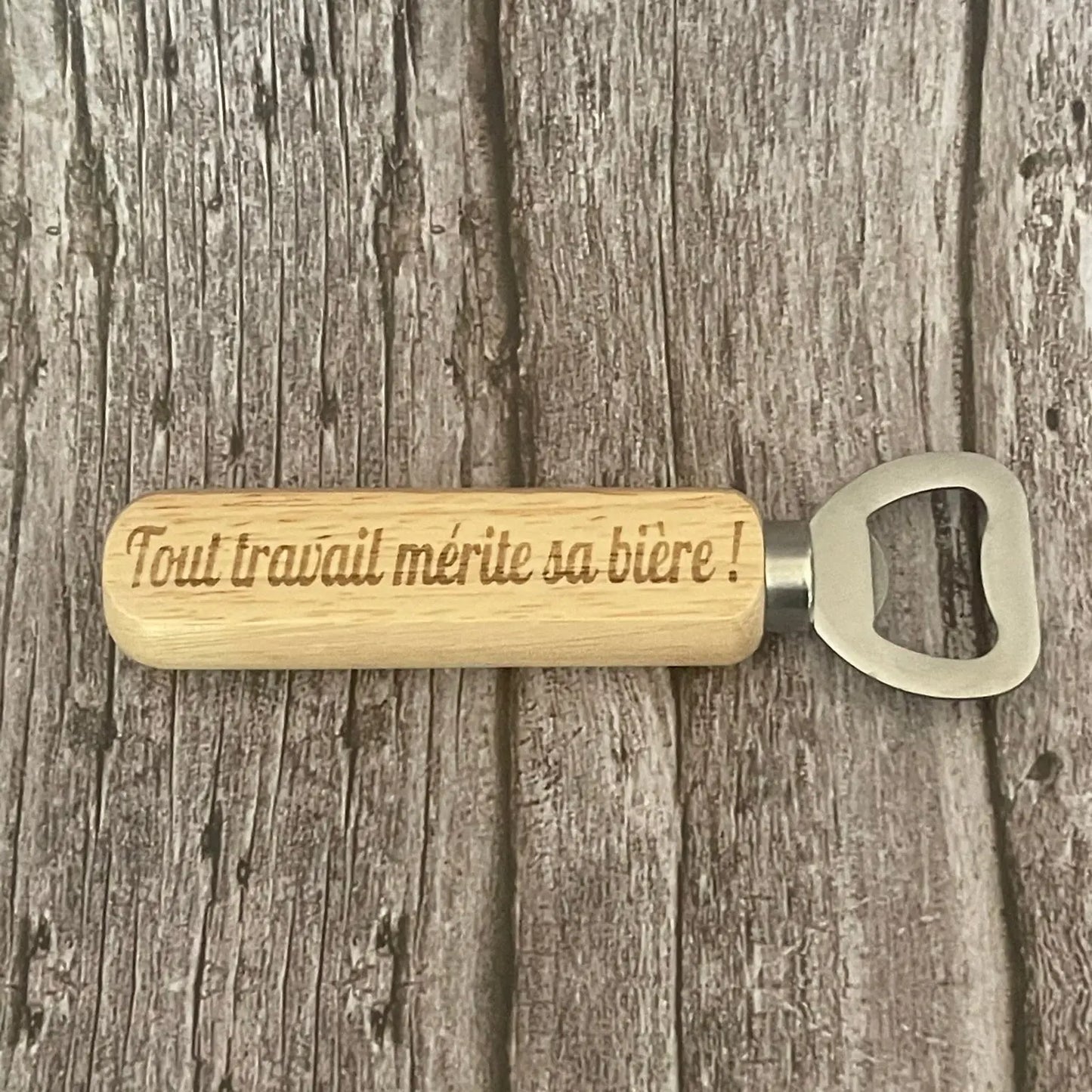 Vue de dessus du décapsuleur en bois clair gravé avec la phrase sur le mérite et la bière.