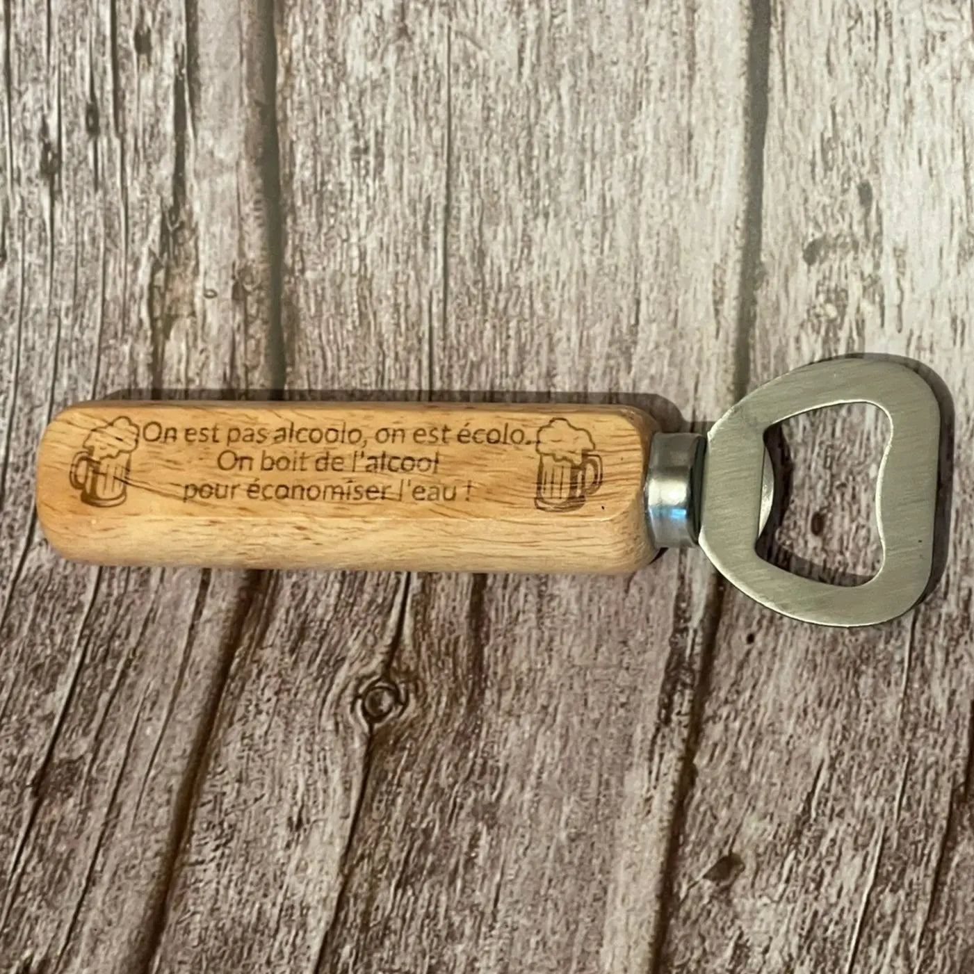 Vue de dessus du décapsuleur en bois clair gravé avec la phrase humoristique sur l'eau et l'alcool.